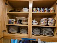 Cabinet view showing stacks of Cornucopia dinner plates, side plates, bowls, mugs, sugar bowl, creamer and serving bowl