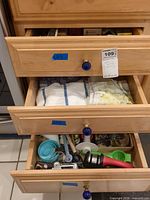 Three kitchen drawers showing towels, utensils and wrap boxes