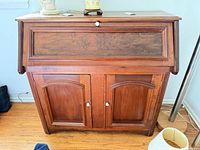 Front view of wood drop-front desk showing cabinet doors and writing surface