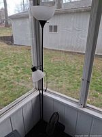 Full view of floor lamp and partial view of table fan in corner