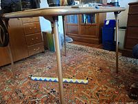 Side view of folding table showing vinyl top and one tubular metal leg