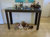 Full view of console table front showing nailhead trim, glass top, and noted damage