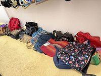 Row of assorted handbags and backpacks on floor