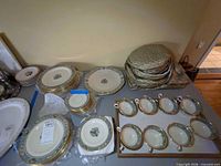 Overall view of stacked plates, soup cups in tray, serving platter, padded storage cases