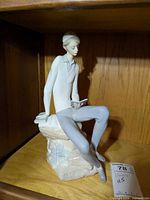 Front view of Lladro figurine showing young man seated on rock with book