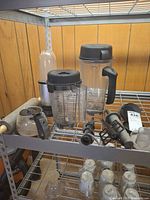 Overall lot on shelving showing blender pitchers, Magic Bullet cup, rolling pin, carafe and small parts