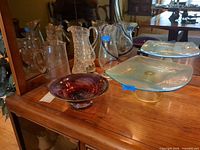 Lot overview showing both pitchers, vase, platter, art glass bowl and oil lamp