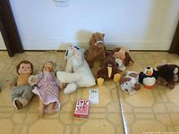 Group shot of two dolls, eight plush animals and deck of cards