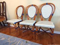 Front view of three matching rattan chairs with patterned seats and backs