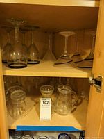 Cabinet upper and lower shelves showing goblets, martini glasses and two pitchers