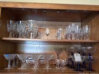 Cabinet showing multiple shelves of stemware in various patterns and sizes