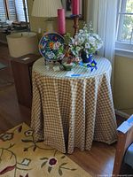 full view of round table covered with gingham cloth, glass top visible