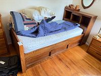 Full view of wooden twin bed with drawers and bookcase headboard