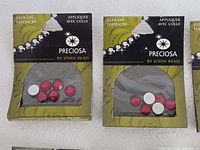 Two packs showing red crystals in olive packaging labelled Preciosa by John Bead Glue-On Flatbacks