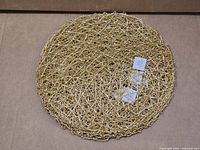 Stack of round gold woven placemats on cardboard surface