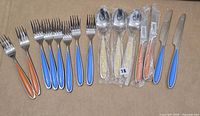 Full set laid out showing forks, spoons, knives, coloured handles