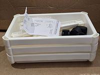 Stacked white plastic trays holding support posts, casters and instruction sheet