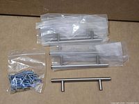 Sealed stainless finish bar pull handles and screws displayed on cardboard