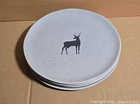 Stack of four grey plates showing deer motif