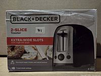 Front of boxed Black+Decker 2-slice toaster showing product image and key features