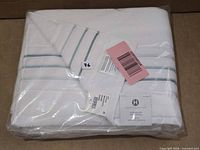 Sealed bath towel showing folded towel with stripe design in plastic