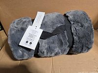 Rolled grey faux fur throw with strap and tags