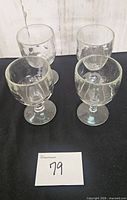 Four clear glass thumbprint goblets arranged on black cloth