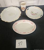 Group shot of all four items: anniversary plate, commemorative cup, floral handled cake plate, oval platter with pink border