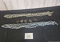 Two metal chains laid parallel with seven S hooks between