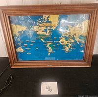 Front view of framed Howard Miller world time clock showing world map and time dials