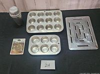 Group overview: two muffin pans, slotted tray, cocktail shaker, packaged boil-over preventer