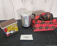 Overall view of percolator, plaid case, and container of corn holders