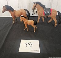 Three flocked horse figures, two adult, one foal, saddle visible