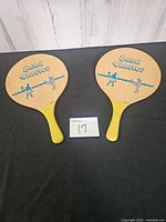 Front view of two Sand Blaster wooden beach paddles showing graphics and handles