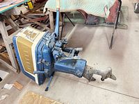Full view of vintage Evinrude outboard motor lying on floor with propeller, handle and housing visible