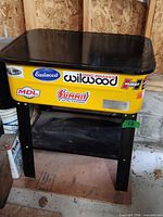 Front view of yellow parts washer with black lid closed on black stand