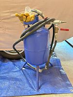 Full view of blue 5-gallon pressure sandblaster with hose and gloves