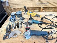 Overall lot with three grinders, discs, wrenches, guards on workbench