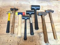 Eight hammers laid out on wooden surface