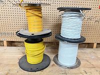 Four spools: two yellow, one white twisted, one light blue cable