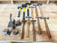 All hammers, mallets, spoon and dollies laid out on workbench