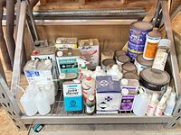 Overall view of shelf with assorted paint and solvent containers