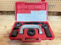 Open red case showing C-frame, forcing screw, cups and adapters