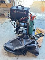 Welder on cart with cylinder, cables, gloves, bag visible
