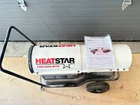 Left side view of HeatStar 140,000 BTU kerosene heater with instruction sheet resting on top