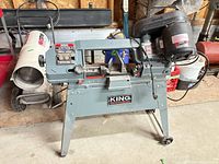 Front view of King Industrial bandsaw on stand with motor and accessories visible