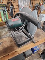 Left front view of Metabo chop saw showing base, vise, motor housing and blade guard