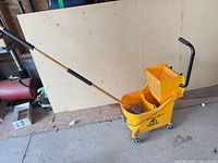 Side view of yellow mop bucket with wringer and Mastercraft mop inserted