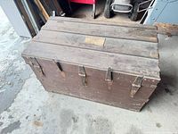 Top view of closed wooden trunk showing slatted lid and front hasps
