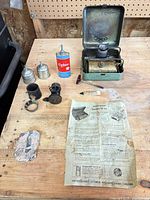 All items laid out showing stove parts, fuel can, tins, instruction sheet